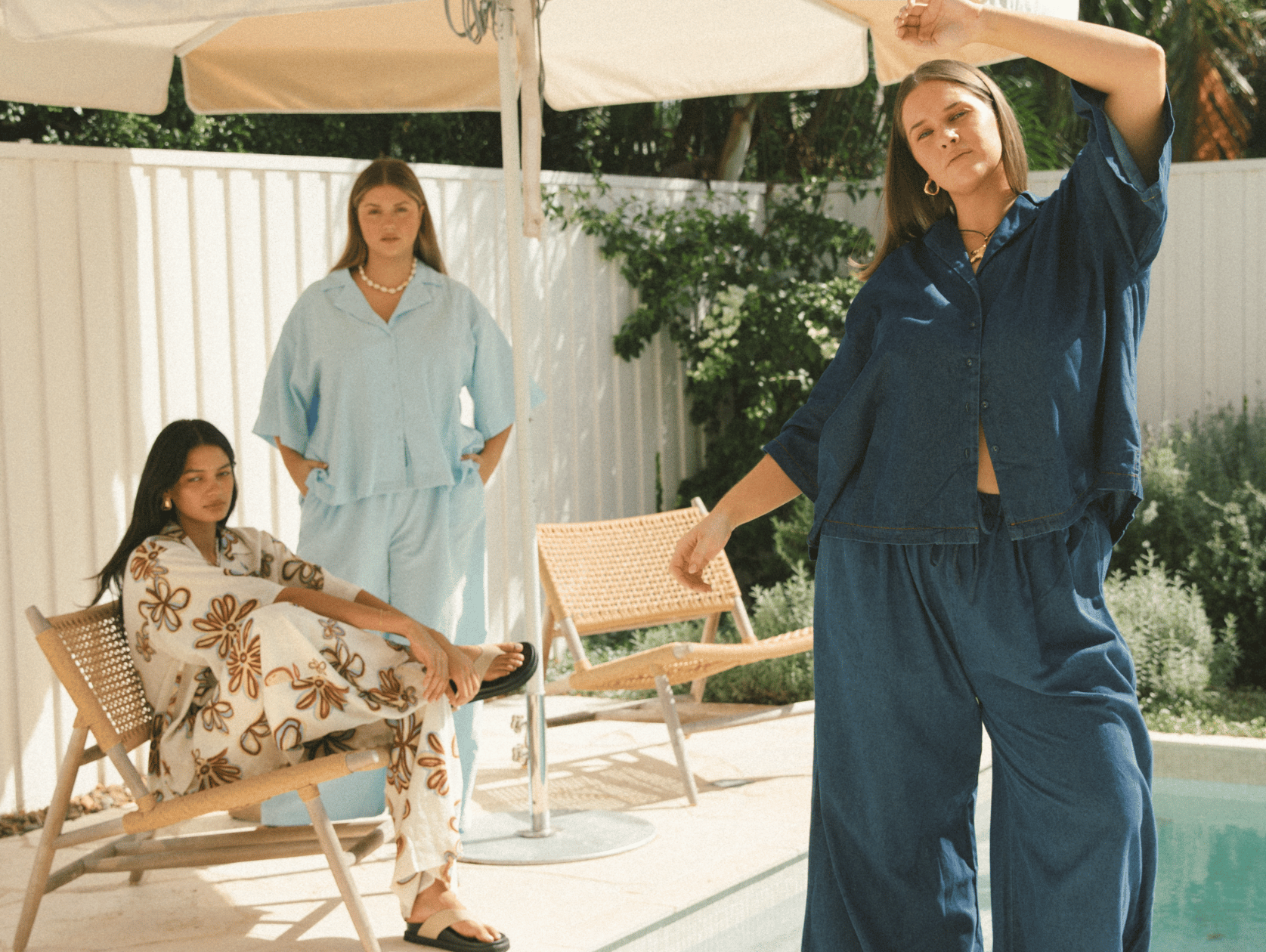 Three women wearing linen printed sets, relaxed sitting on stairs outside in a fashionable manner