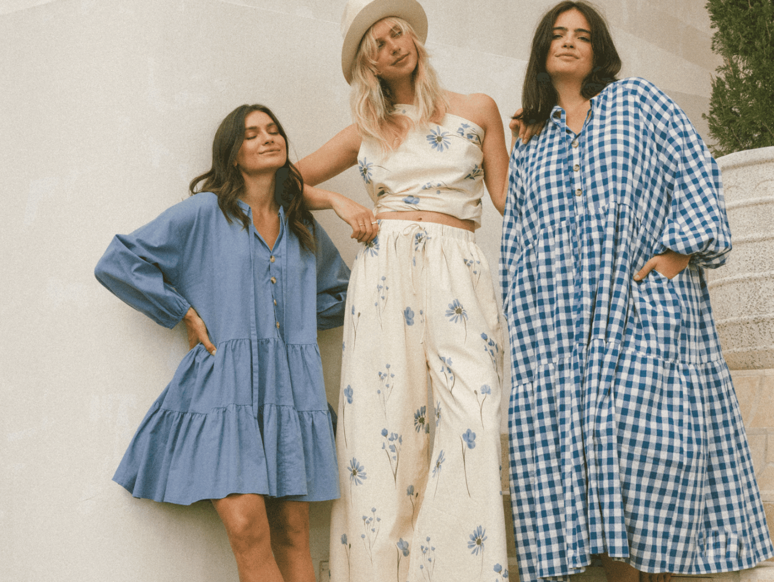 Two women standing next to each other with their hands in each others jean pockets. It's a close up of two pairs of jeans, blue and black.