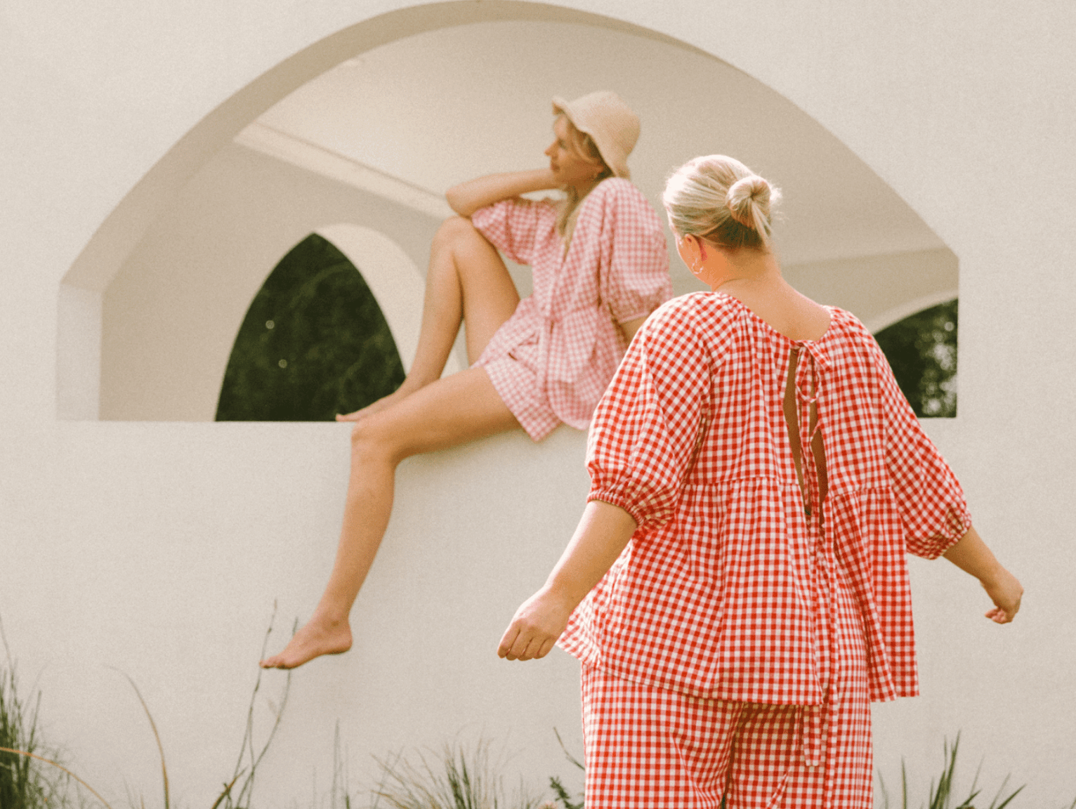 Two women standing next to each other with their hands in each others jean pockets. It's a close up of two pairs of jeans, blue and black.