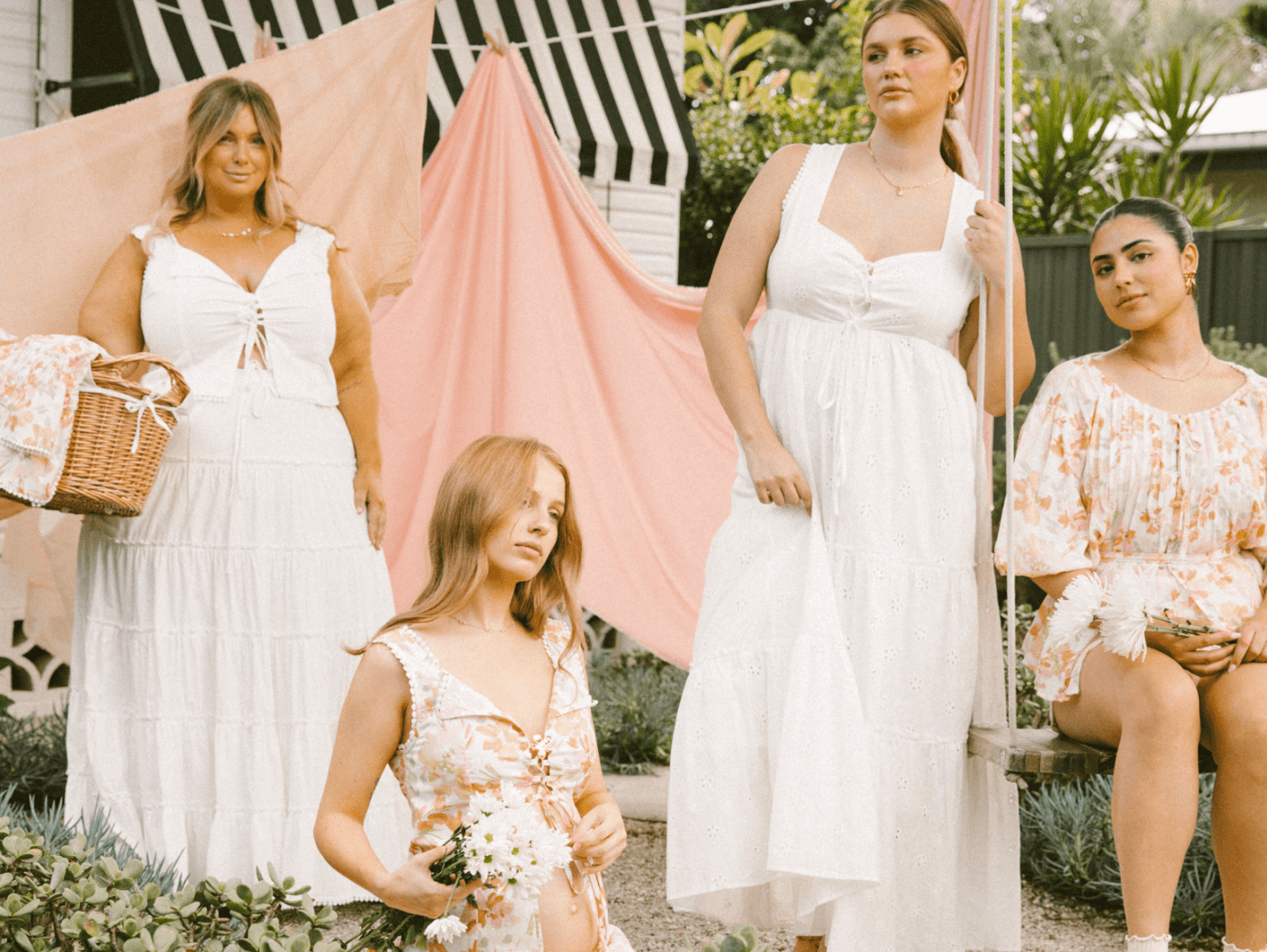 Four women wearing floral and floaty outfits in a garden