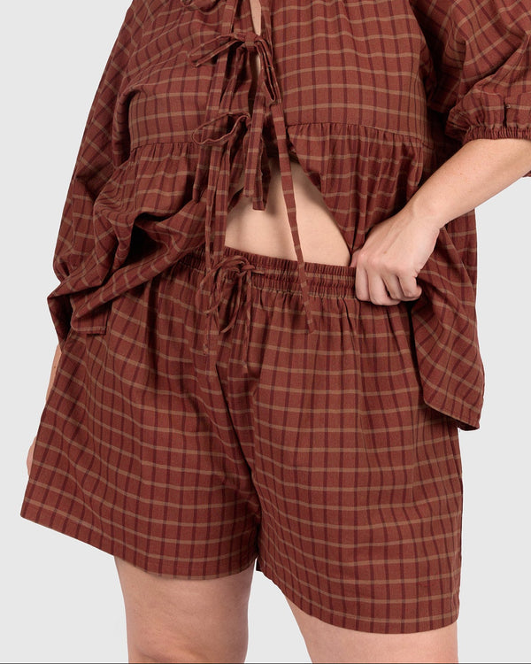 Woman wearing a brown plaid outfit on a white background