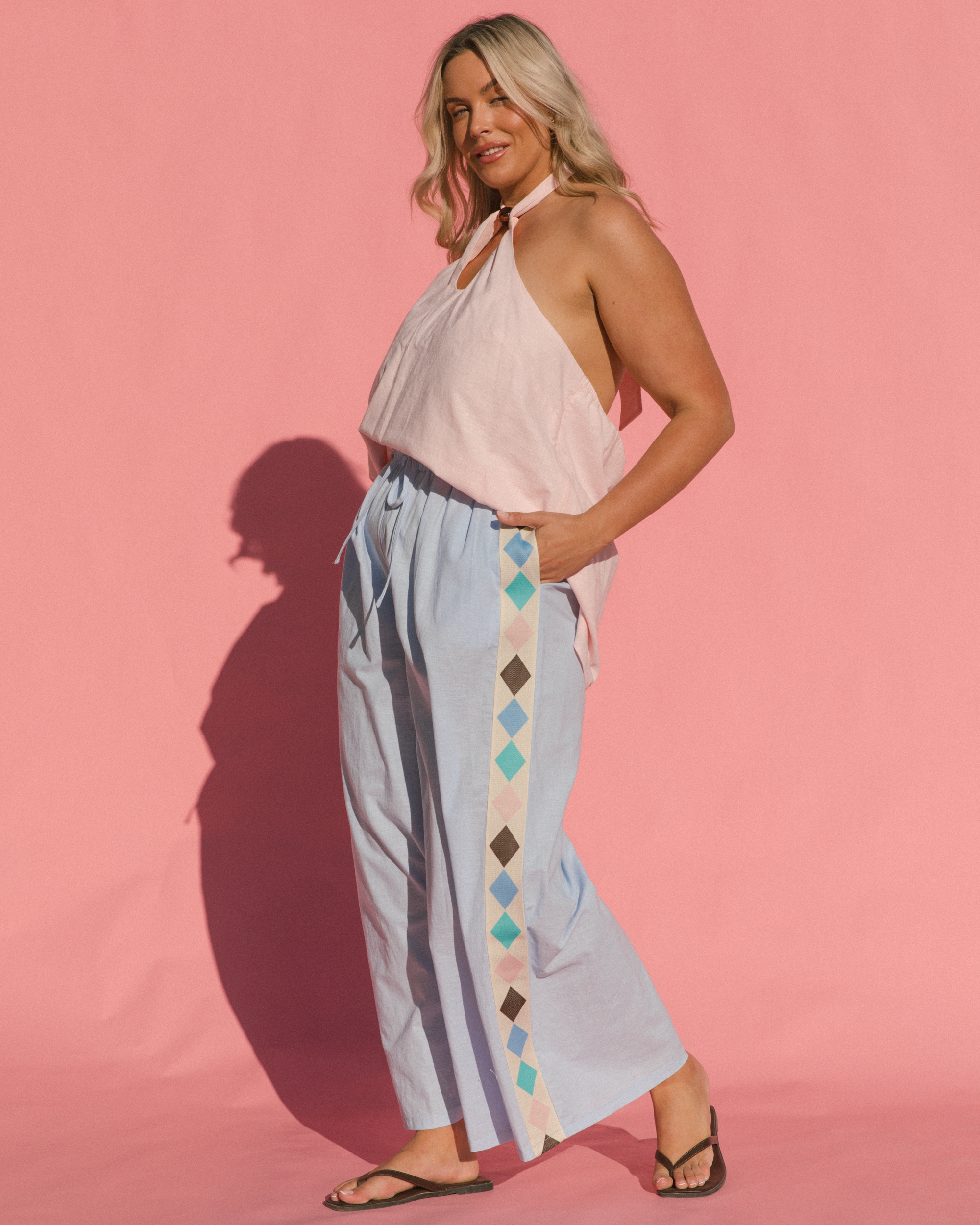 Woman wearing relaxed spring fashion look consisting of strapless top & long flowy pants.