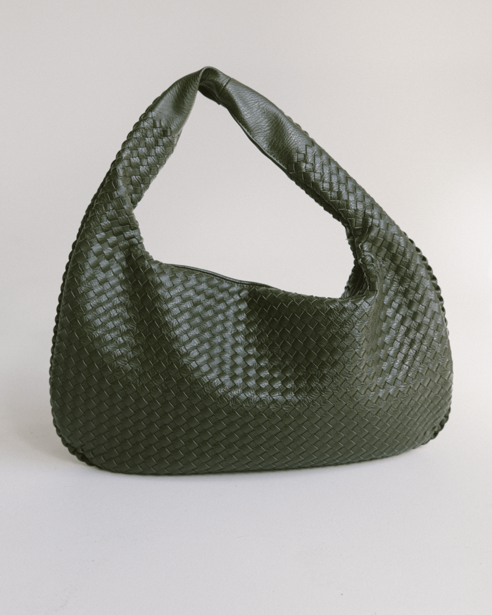 Stylish green woven handbag on a light gray background