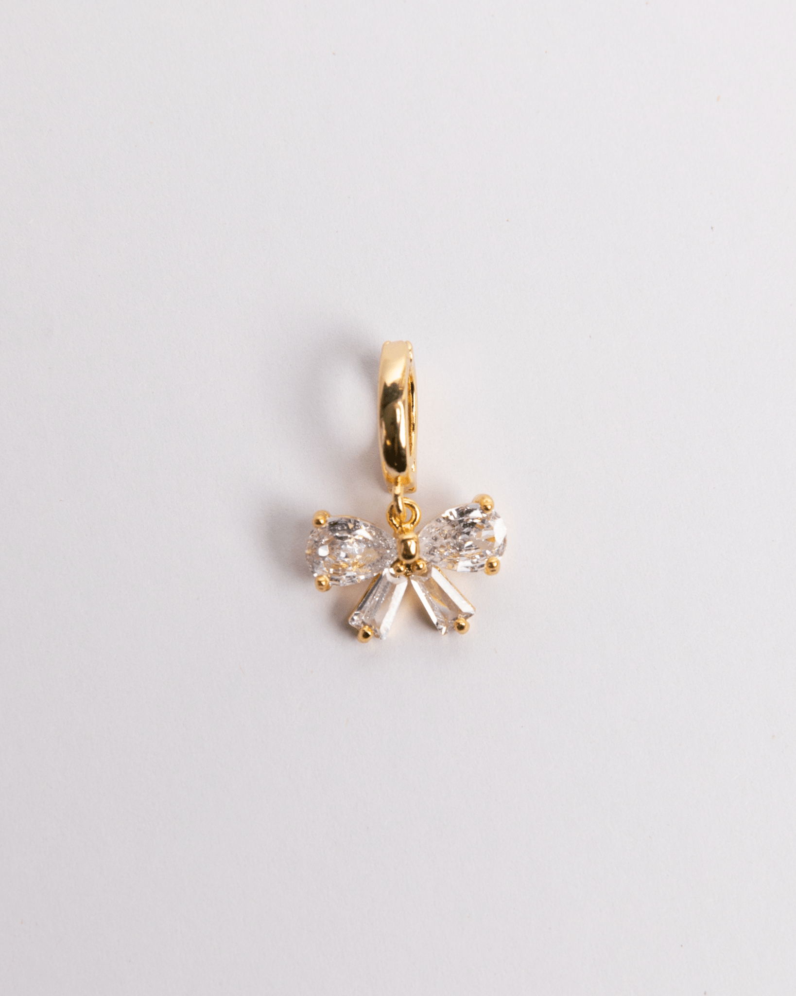 A gold-plated stainless steel and crystal bow charm with a secure clasp on a white background.