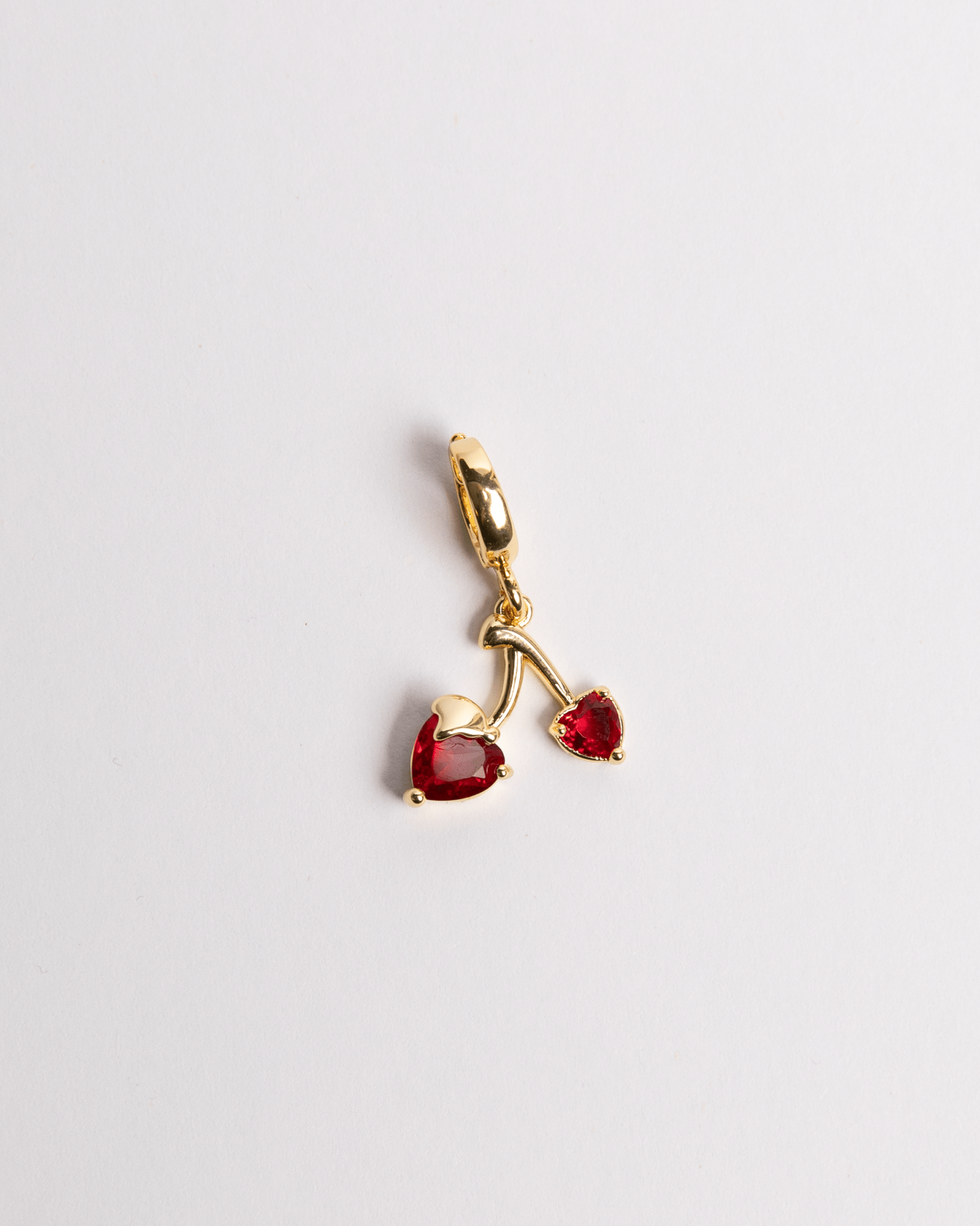 A gold-plated stainless steel charm featuring a cherry with heart-shaped leaves and red gemstones.