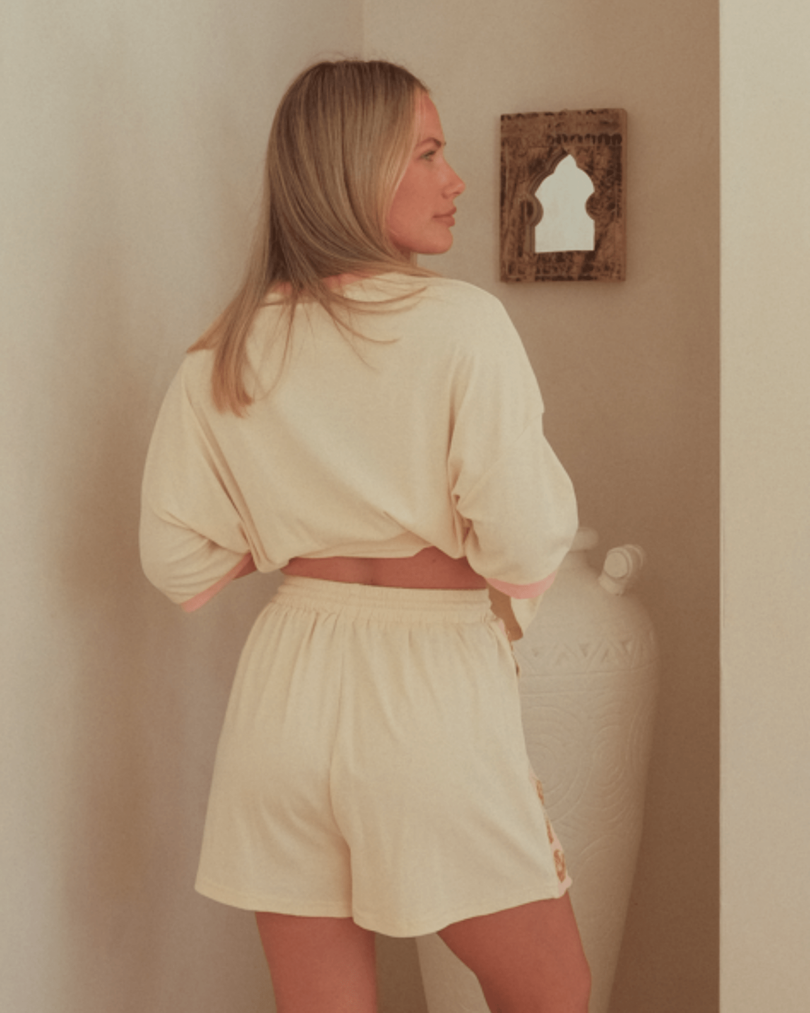 Woman wearing beige lounge shorts with elasticated waist band.