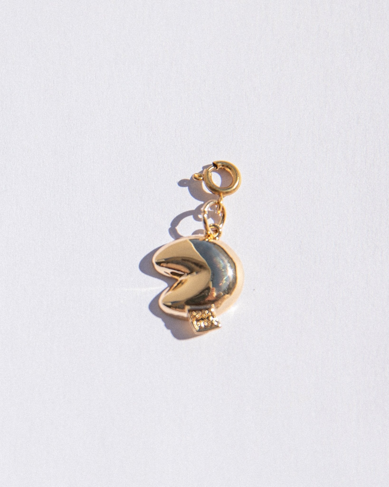 Gold charm with a fortune cookie pendant on a white background