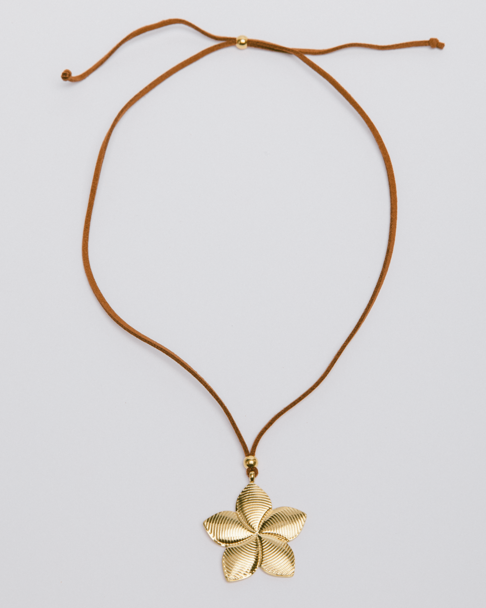 Gold frangipani pendant on an adjustable cord chain.