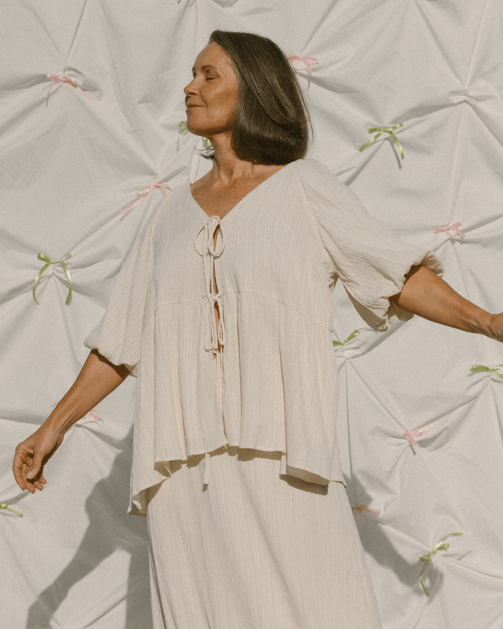Woman wearing cream coloured crepe oversized flowy shirt & long skirt set.