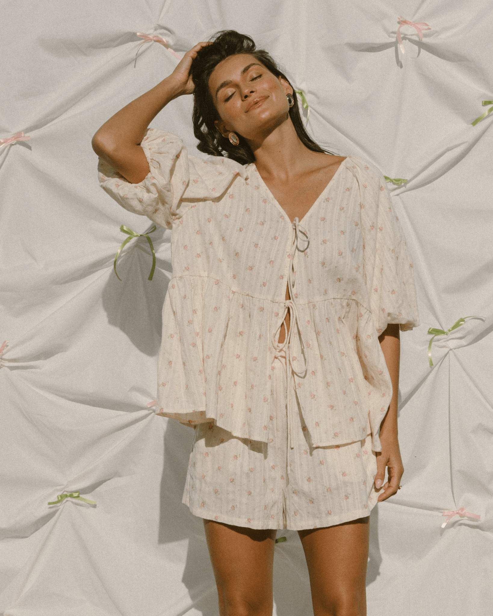 Woman wearing a trendy cottage-core outfit with a tie up top and flowy shorts.