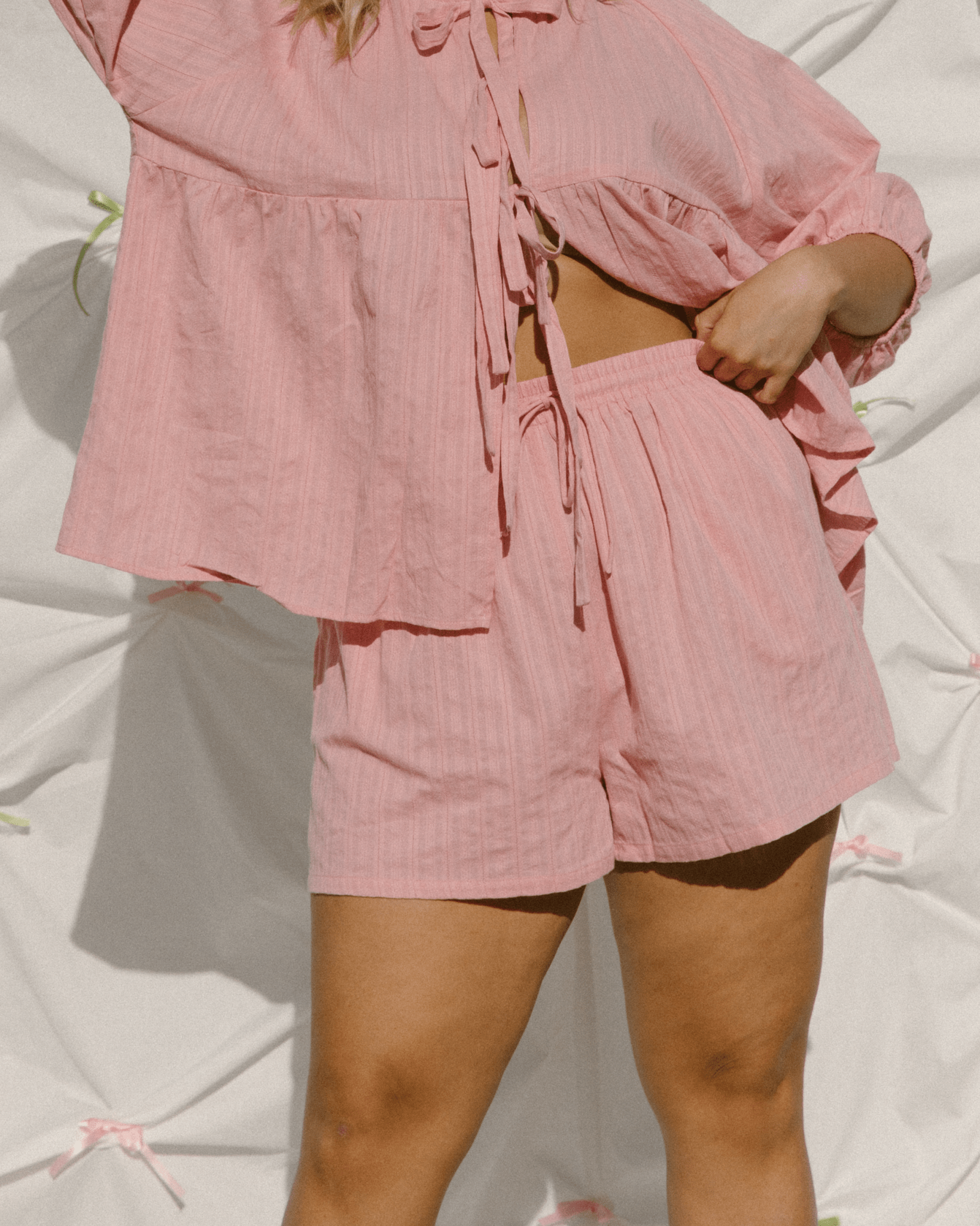 Woman wearing trendy pink co-ord set with tie up shirt and drawstring shorts.