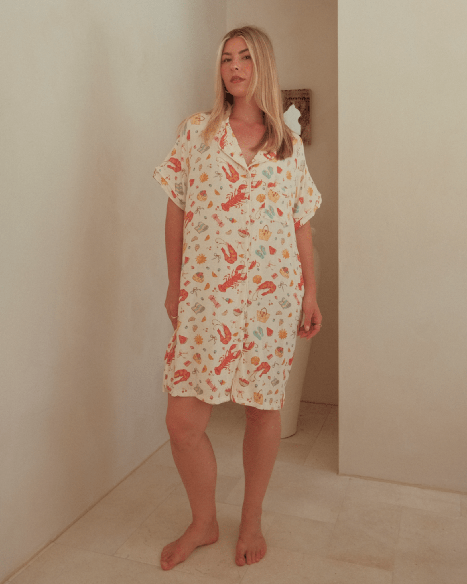 Woman wearing a Australian Christmas themed nightshirt in a minimal indoor setting