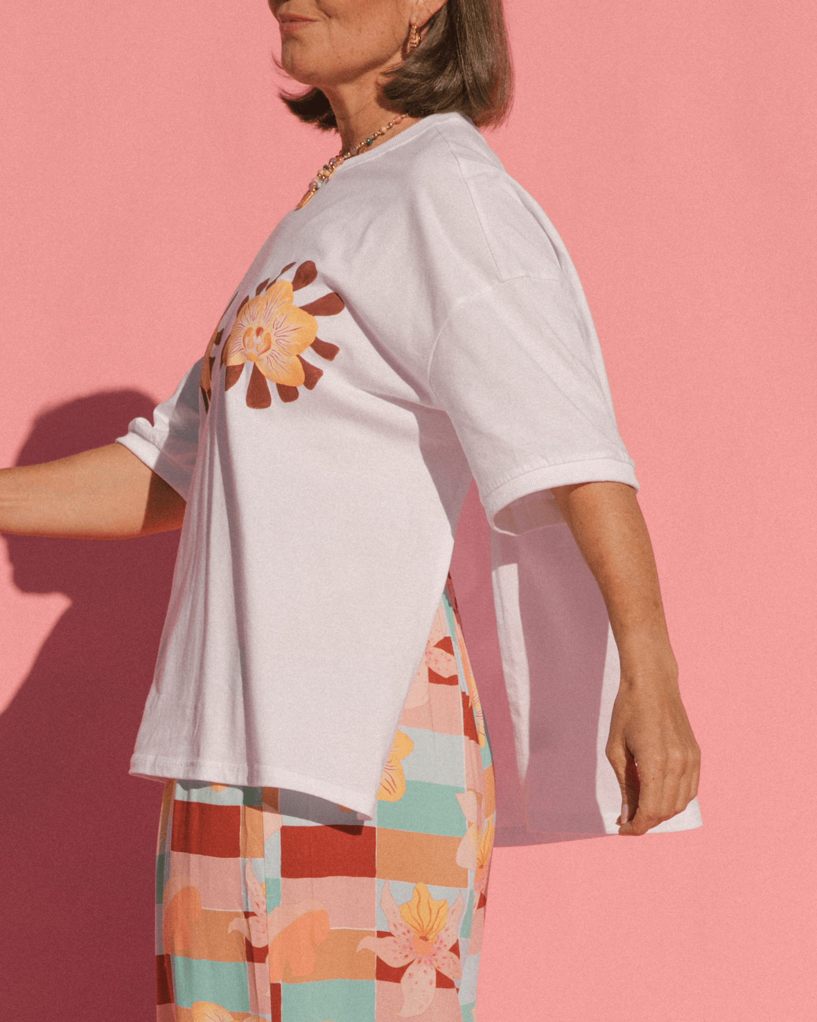 Woman wearing a breastfeeding accessible white graphic oversized tshirt with the side-seam zippers unzipped.