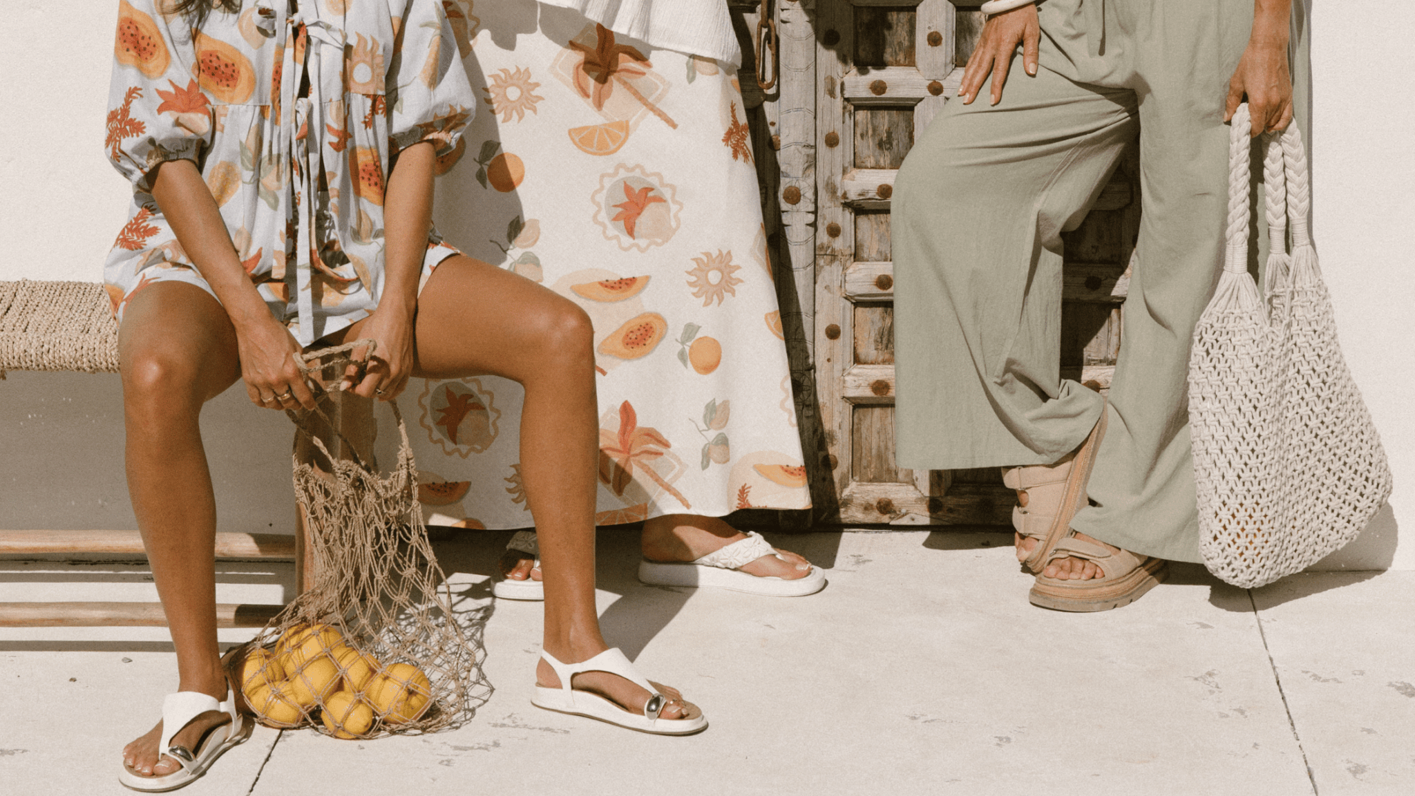 Three women wearing linen printed sets, relaxed sitting on stairs outside in a fashionable manner