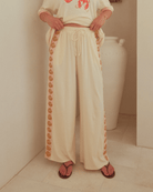Woman wearing high-waisted beige wide-legged pants with drawstring waist. 