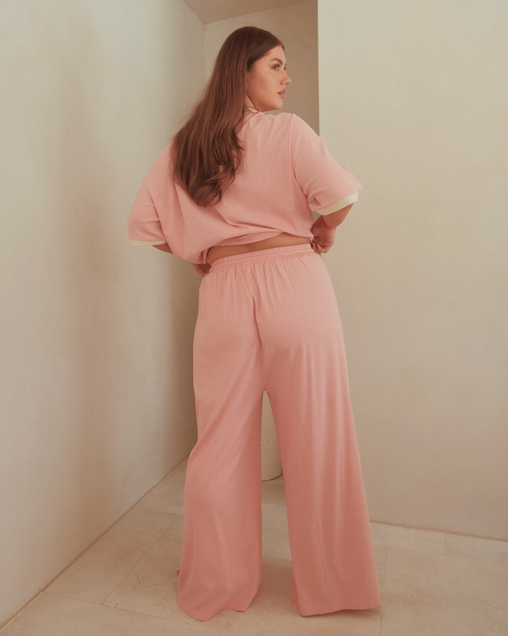 Woman wearing pink relaxed high-waisted lounge pants and oversized shirt. 