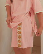 Person wearing a pink outfit with shell patterns on a plain background