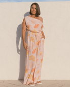 Woman wearing a matching floral set with a off the shoulder crop top and long pants in a breathable fabric. 