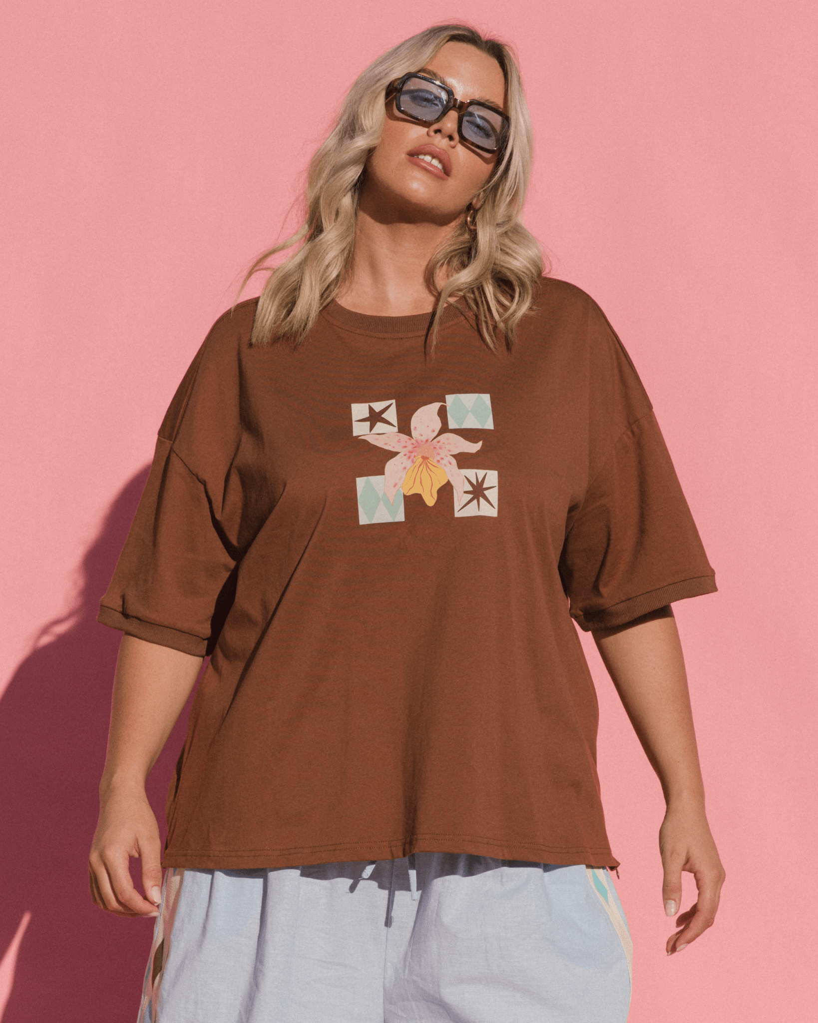 Woman wearing brown slouch-fit oversized t-shirt with a spring graphic print on the front. 
