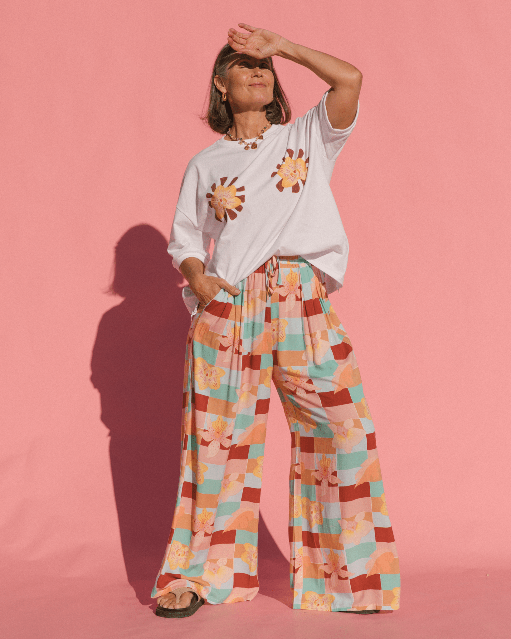 Woman wearing stylish oversized white graphic tee tucked into high-waisted flowy cotton geometric check pants. 