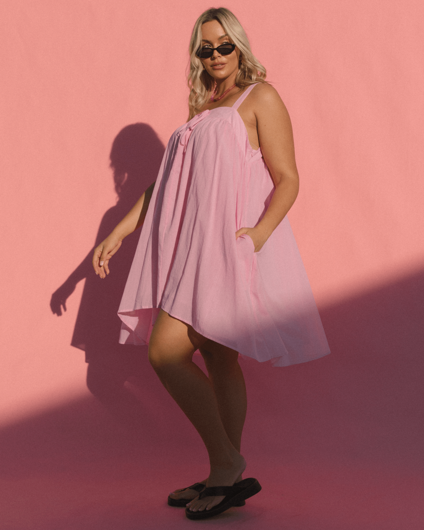 Women wearing bubblegum pink sleeveless swing dress. 